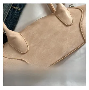 Detail of beige leather handbag showing fine stitching and smooth semi-circular side curve
