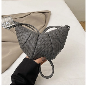 Close-up of hand-woven texture and crescent shape on a dark grey premium handbag