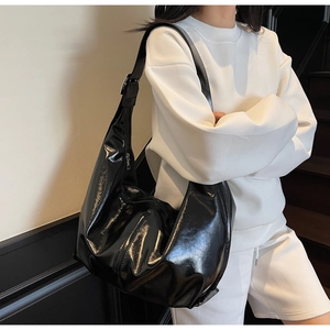 Sac hobo noir brillant avec bandoulière réglable porté avec une tenue décontractée