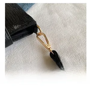 Détail du crochet en métal doré et texture à paillettes noires du sac bandoulière