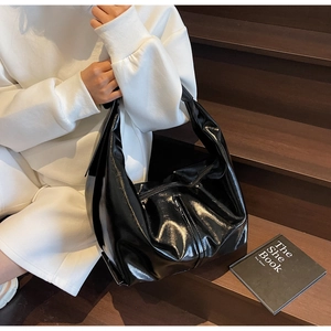 Détail d'un grand sac cabas noir brillant en similicuir avec large bandoulière d'épaule