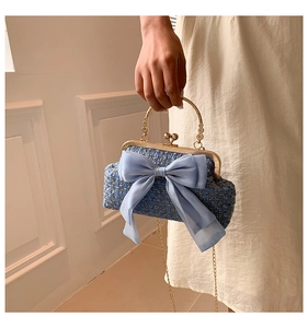 Detail of tweed evening bag with a light blue chiffon bow and golden metal handle