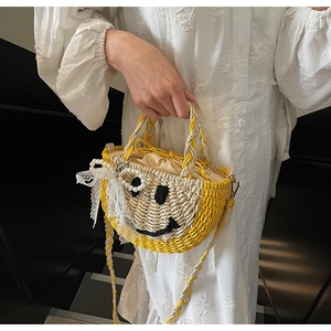 Detail of straw woven bag featuring a smiley face embroidery and lace bow accessory