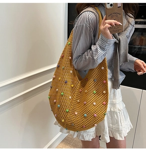 Close-up of ginger yellow crochet shoulder bag with colorful beads and knit hollow texture