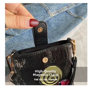 Détail du fermoir magnétique doré sur un mini sac à bandoulière noir avec paillettes