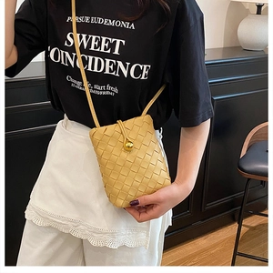 Detail of yellow woven mobile phone bag with leather texture and gold ball clasp