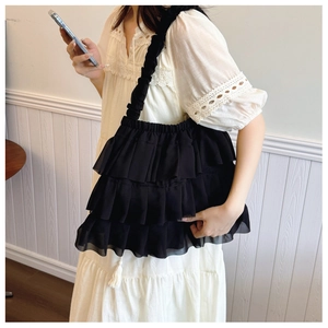 Close-up of black layered chiffon ruffled shoulder bag with pleated straps for women