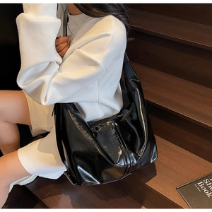 Gros plan sur le sac hobo en cuir verni noir brillant avec des plis et bandoulière