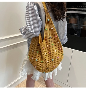 Detail of yellow knit tote bag with colorful beads worn by a model in a modern interior