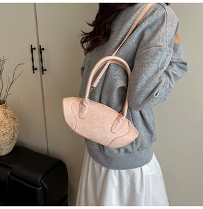 Detail of light pink textured handbag showing metallic hardware and detachable strap