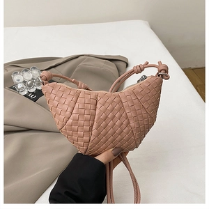 Close-up of hand-woven croissant crossbody bag in nude pink with decorative knot detail