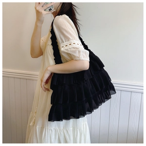 Detail of black multi-layered ruffle tote bag styled with a white lace bohemian dress