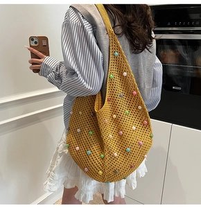 Detail of yellow knit crochet beach bag with colorful pearl beads and hollow texture