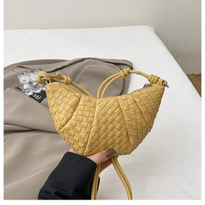 Close-up of yellow hand-woven crescent bag with premium leather texture and zip closure