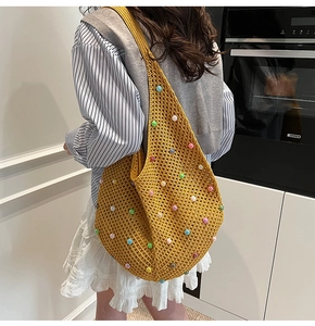 Close-up of yellow knitted hobo bag with colorful pearl beads and texture details
