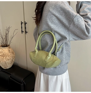 Light green oval leather handbag with adjustable strap shown in a modern interior setting