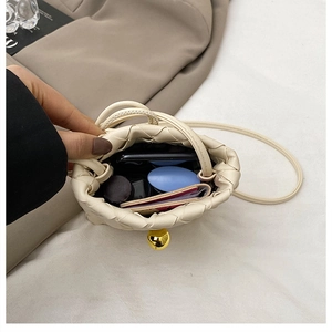 Close-up of woven bucket bag showing interior space with phone and golden sphere lock