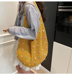 Close-up of yellow crochet tote bag with colorful pearl embellishments and woven texture