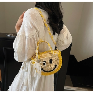 Detail of straw bag featuring a yellow smiley face with pearl chain and lace bow charm