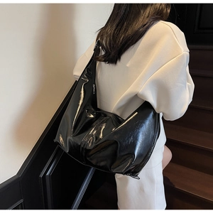 Détail d'un grand sac bandoulière noir brillant montrant sa texture lisse et son allure chic