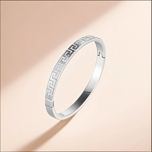 Close-up of silver stainless steel bangle with Greek key meander pattern engraving