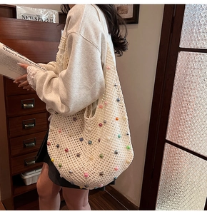 Detail of hand-woven beige tote bag featuring colorful pearl beads and hollow knit texture