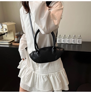 Detail of black matte leather handbag with streamline stitching and slim shoulder strap