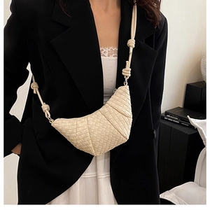 Detail of hand-woven cream leather crossbody dumpling bag with decorative shoulder knots