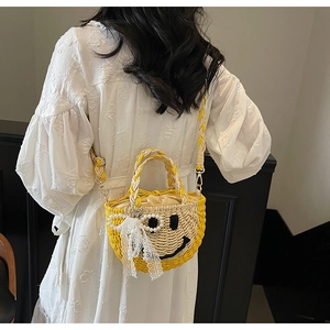 Detail of hand-woven straw bag with smiley face pattern and pearl bow charm
