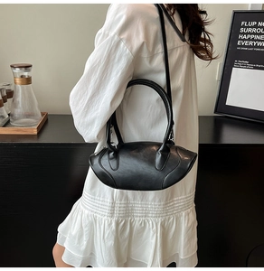 Detailed view of a sleek black oval-shaped handbag with premium matte finish texture