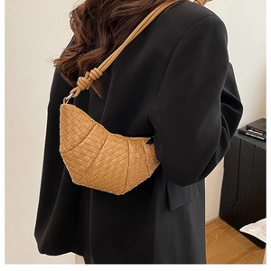 Detail of a brown woven leather dumpling bag styled with a professional black suit blazer