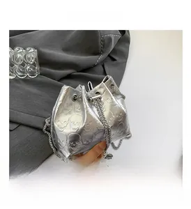 Detail of silver drawstring bucket bag featuring embossed skull textures and chain strap