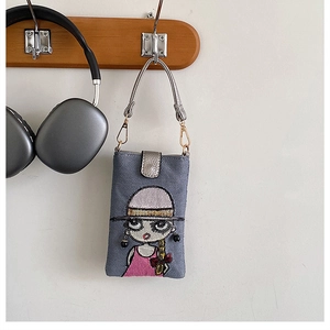 Détail de la pochette téléphone en denim gris avec broderie fille et accessoire de mode