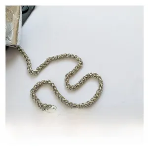 Detail of silver metallic woven chain strap and textured leather finish on shoulder bag