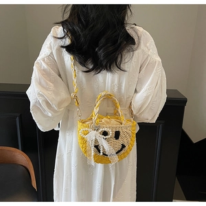 Detail view of woven straw bag featuring a cute smiley face and lace pearl decoration