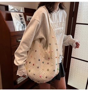 Detail of beige crochet net bag featuring colorful pearl beads and hollow knit texture