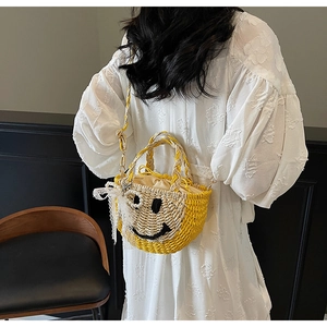 Detail of straw woven bag with yellow smiley face design and pearl lace charms