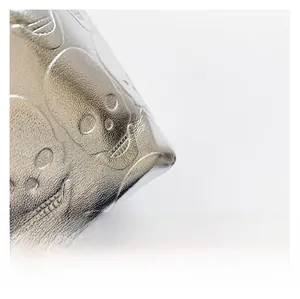 Detail of silver metallic leather with embossed 3D skull patterns and punk style texture
