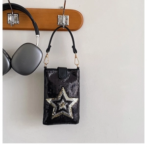 Détail d'un sac téléphone à paillettes noires avec étoile dorée sur un crochet en bois