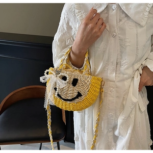 Close-up of woven straw handbag featuring a lace bow and yellow smiley face detail