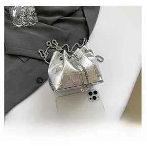Mini silver skull embossed drawstring bucket bag size comparison with a smartphone