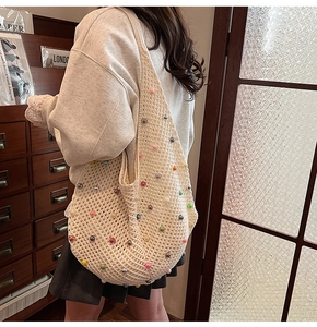Detailed view of beige crochet shoulder bag with colorful pearl beads on casual hobo knit