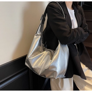 Sac hobo argenté métallisé porté par un mannequin, doté d'une bandoulière noire réglable