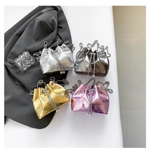 Close-up of four metallic drawstring bucket bags with skull patterns and chain straps
