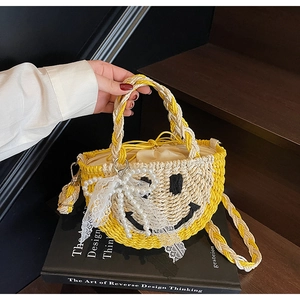 Detail of straw woven handbag with black smiley face pattern and delicate lace trim detail
