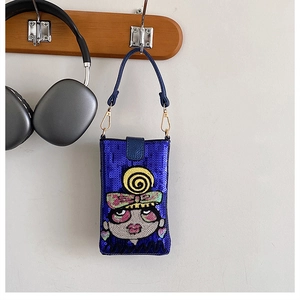 Détail du sac bandoulière à paillettes bleues avec motif fille sur cintre en bois