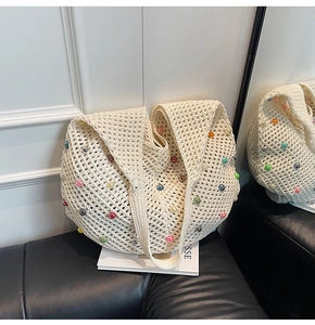 Detail of hand-knitted hollow mesh tote bag with colorful pearl beads on casual strap
