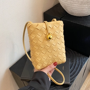 Chic yellow woven leather mini crossbody bag with a distinctive gold sphere clasp closure