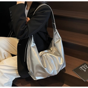 Détail d'un sac à bandoulière argenté métallisé avec fermeture éclair verticale
