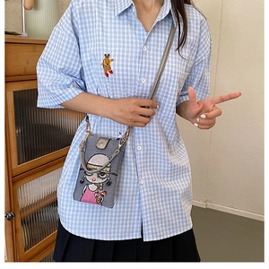 Détail de la petite sacoche grise avec broderie de fille de dessin animé et fine bandoulière